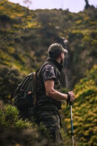 Un homme avec un équipement de randonnée explore un paysage forestier luxuriant, incarnant l'aventure et la nature.