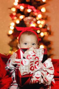 un bébé assis sur un canapé tenant un cadeau emballé