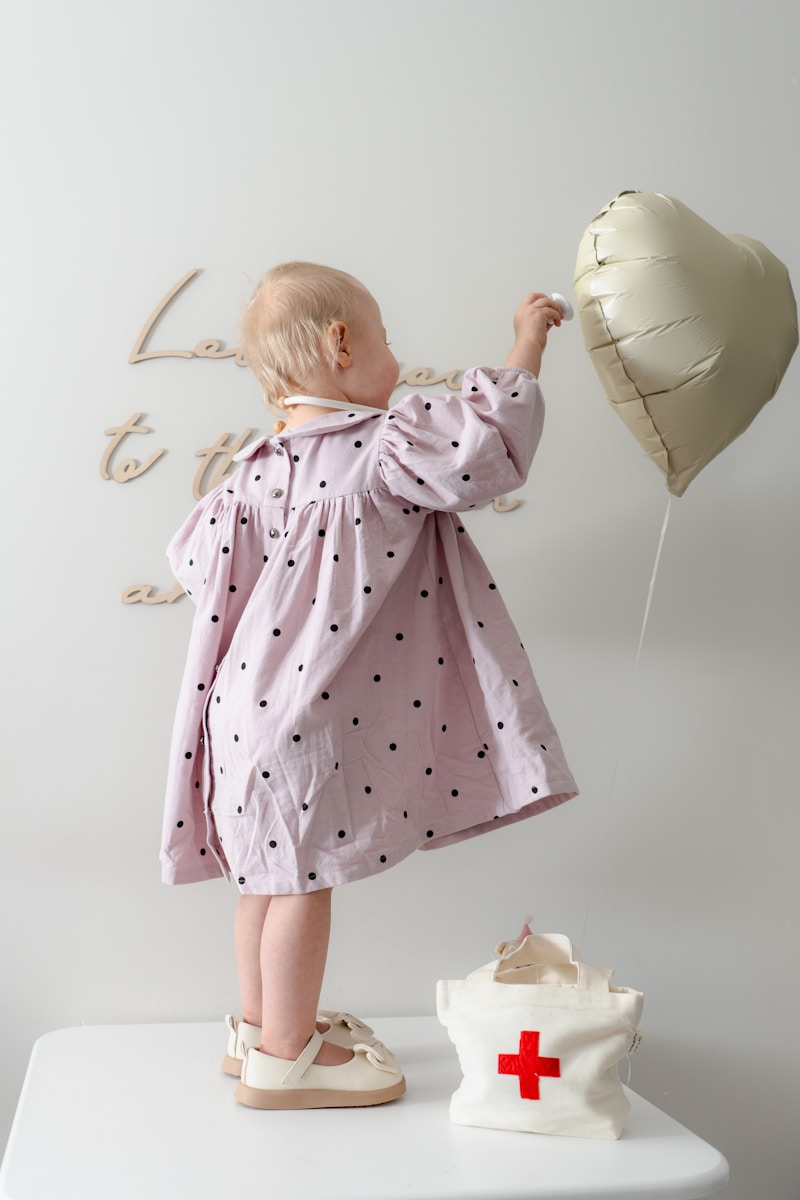 Une petite fille en robe rose tenant un ballon